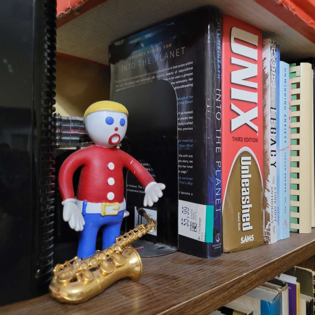 posable Mr. Bill with saxophone posed in front of a stack of rpi's, the router on his right, books on his left
